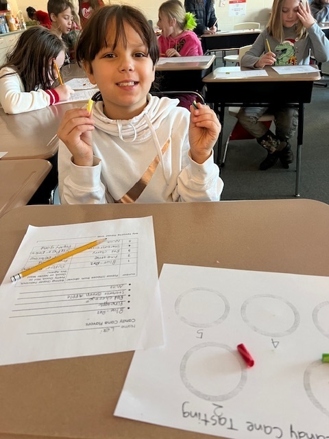 Student smiling while holding pieces of candy canes