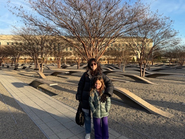 Lilly and her mom Sarah standing in front of the memorial