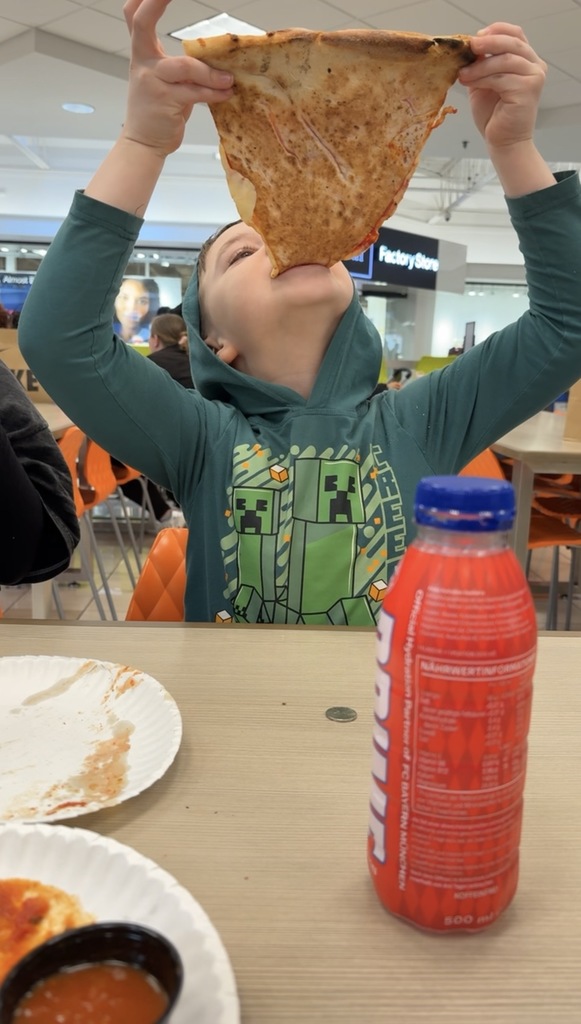 Bailey taking a bite of a huge piece of pizza