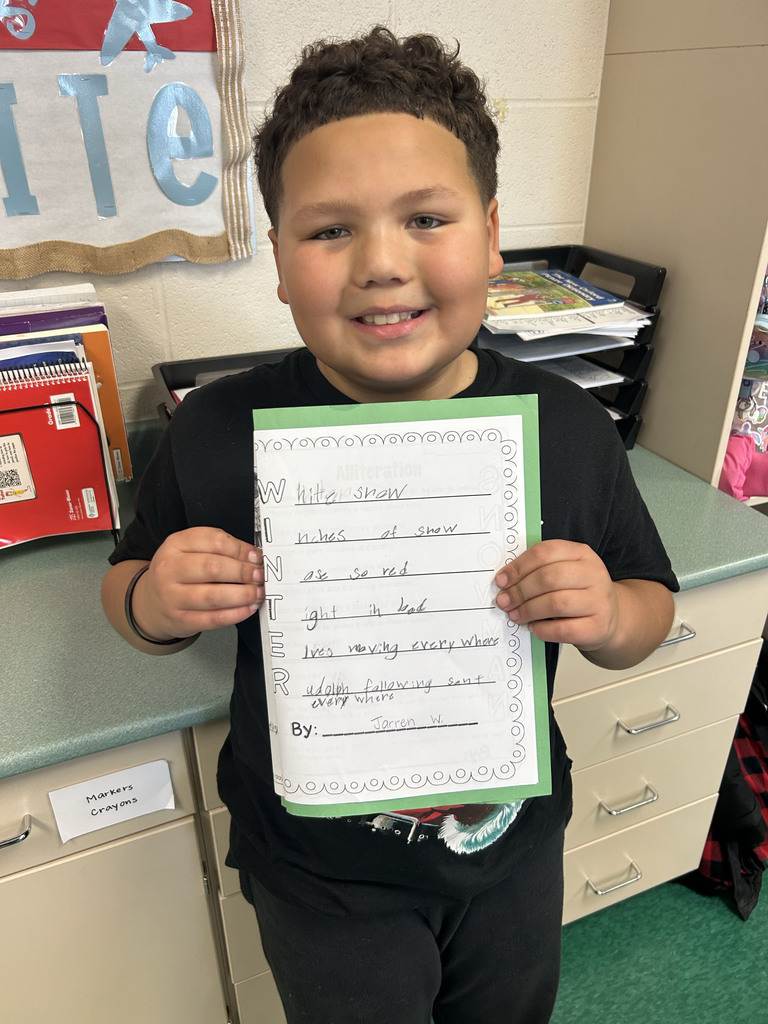 Student holding their poem and smiling
