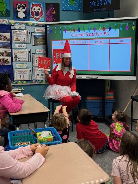 Lesli Waller dressed as an elf on the shelf reading