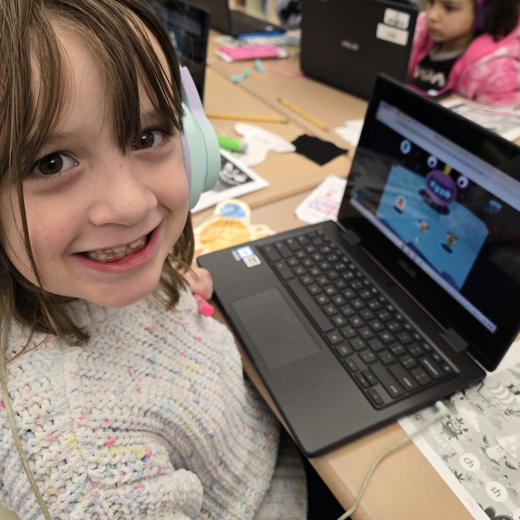 Student smiling with her chromebook in the background