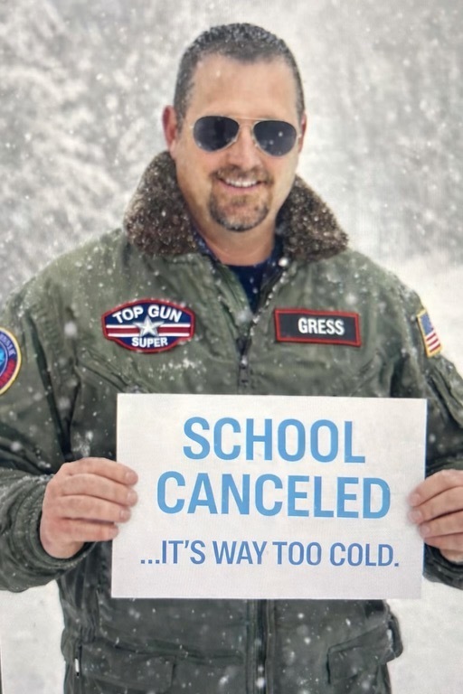 Mr. Gress dressed as an aviator holding a sign that says "School cancelled... It's way too cold"