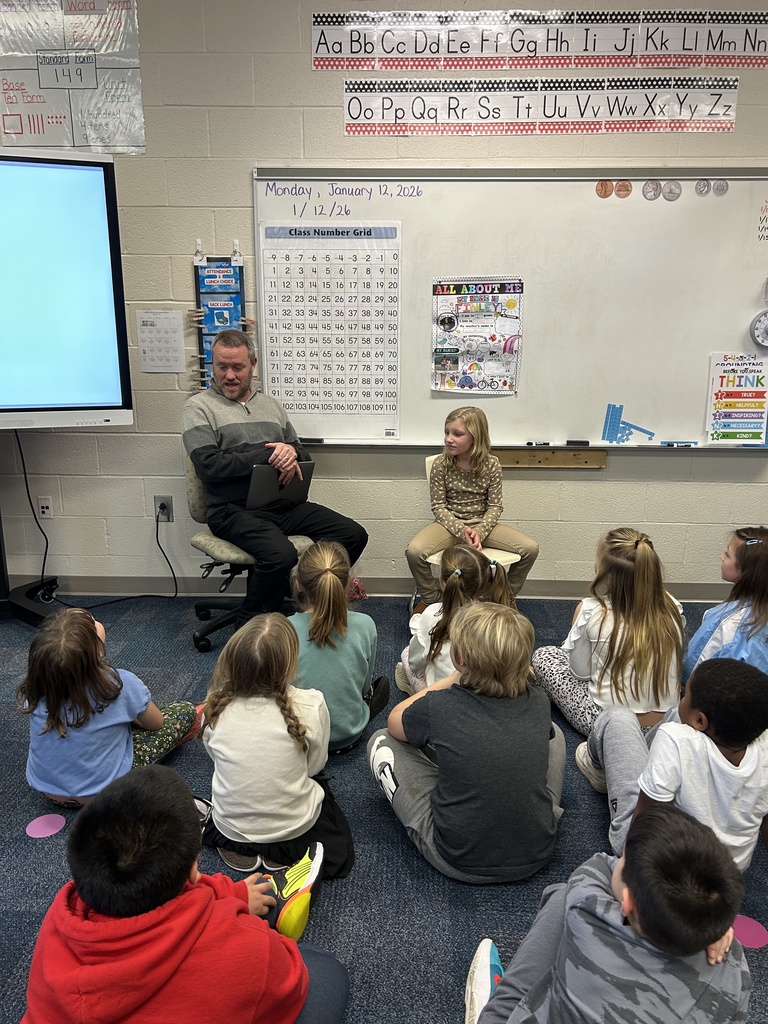 Chad Morris talking to the students while his daughter, Finley, sits beside him