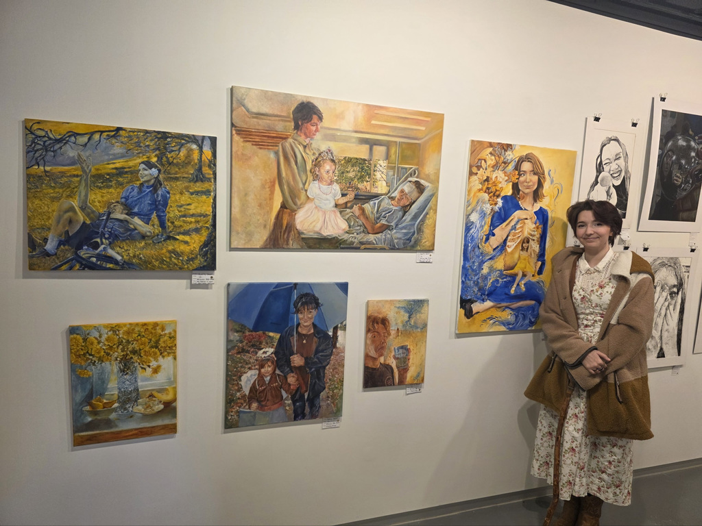 Audrey Howell standing next to her artwork hanging in the gallery