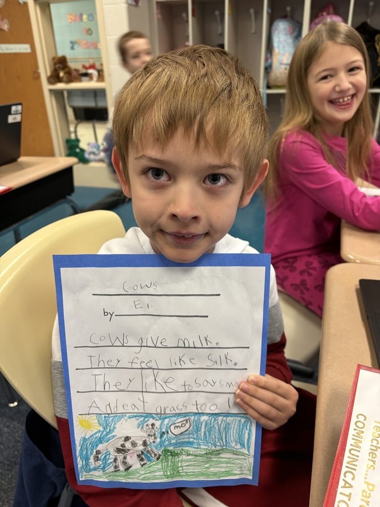 Student holding his poem about cows: "Cows give milk. They feel like silk. They like to say moo And eat grass too."