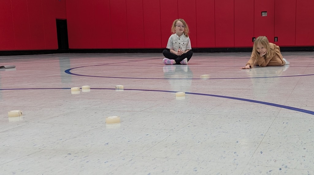 Student sliding rolls of tape like they would  for curling