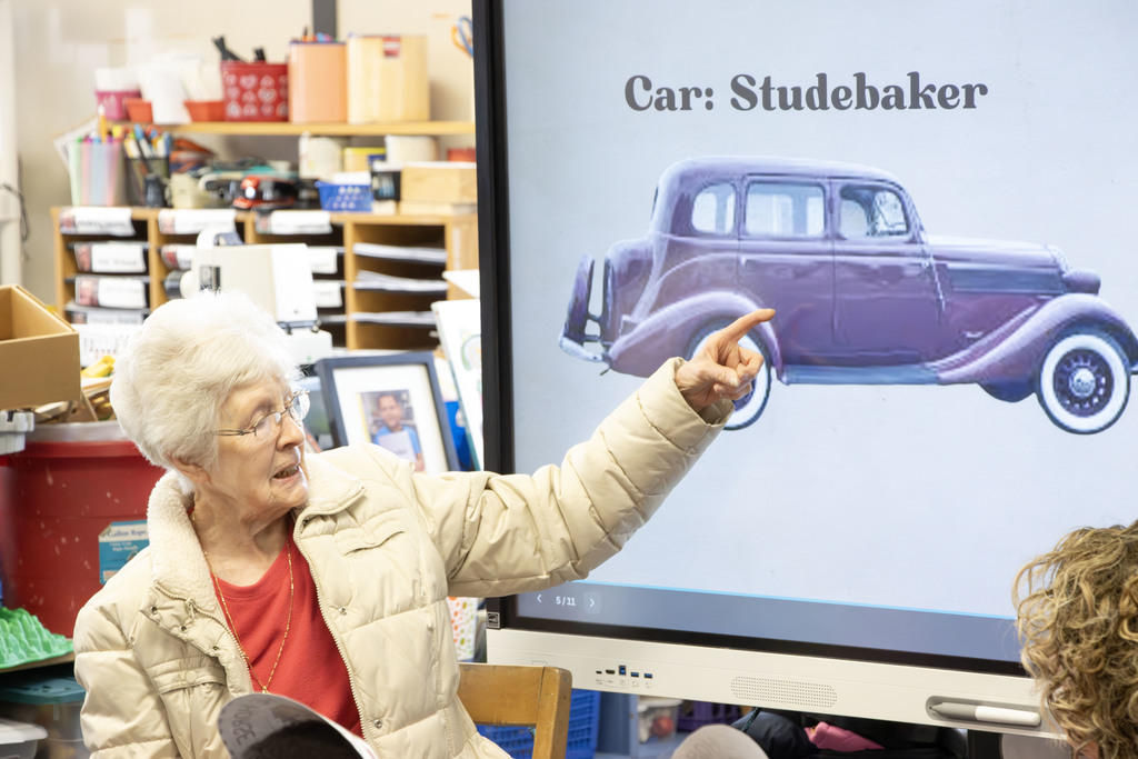 Ms. Haynes pointing at a screen with a picture of an old car she used to own