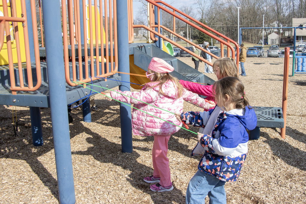 Students use jump ropes wrapped around bars on the play ground to simulate flossing teeth