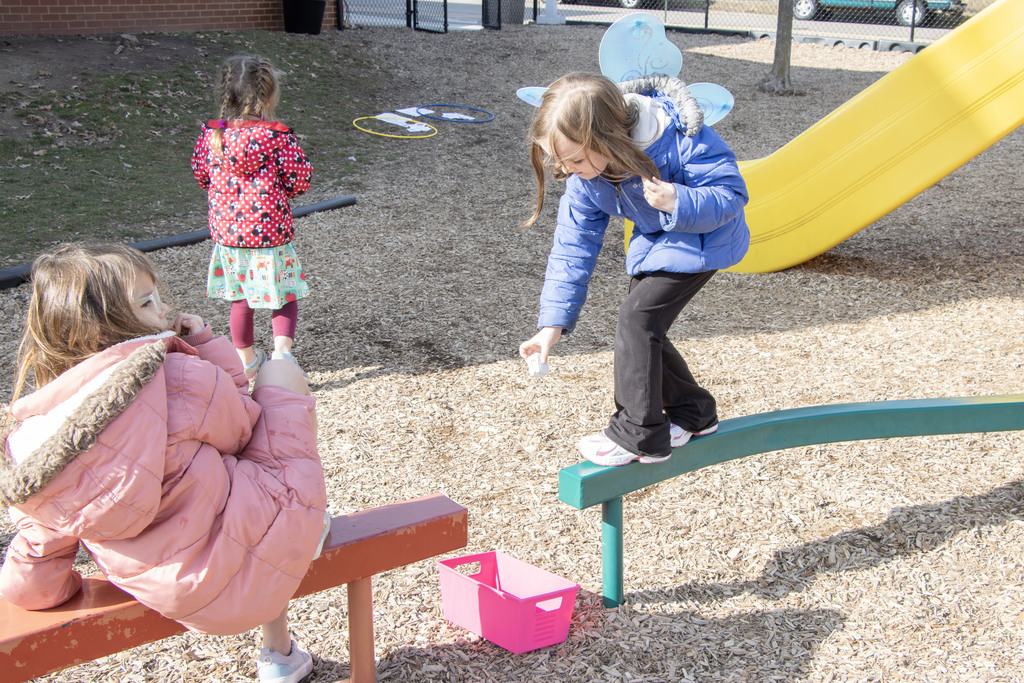 A student wearing fair wings walk on a balance beam to deliver a tooth to a box