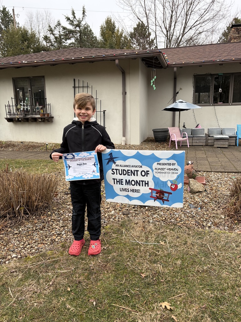 A student holding his certificate and standing by his yard sign