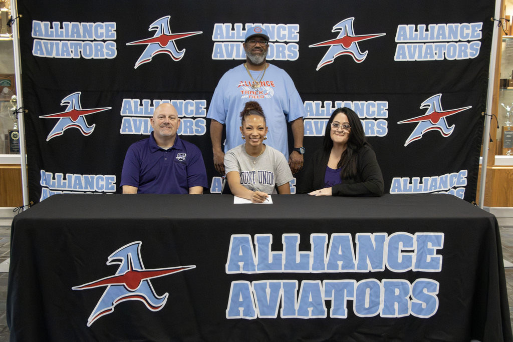 Kyliana smiling with her parents sitting next to her and her coach standing behind