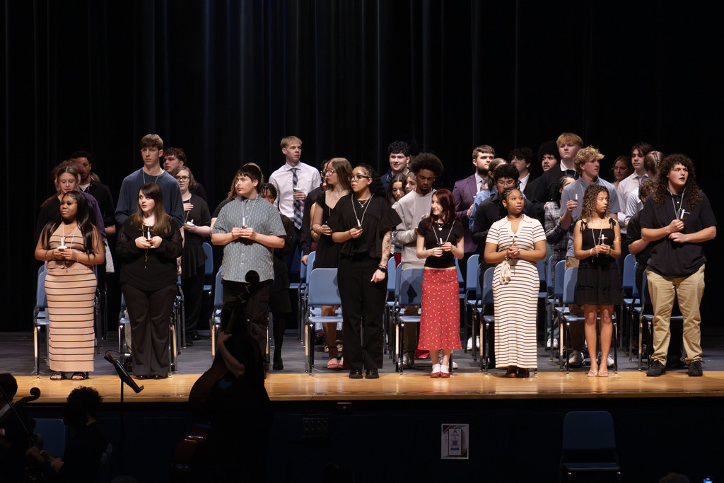The 46 students standing on stage holding lit ceremonial candles while reciting the NHS Pledge 