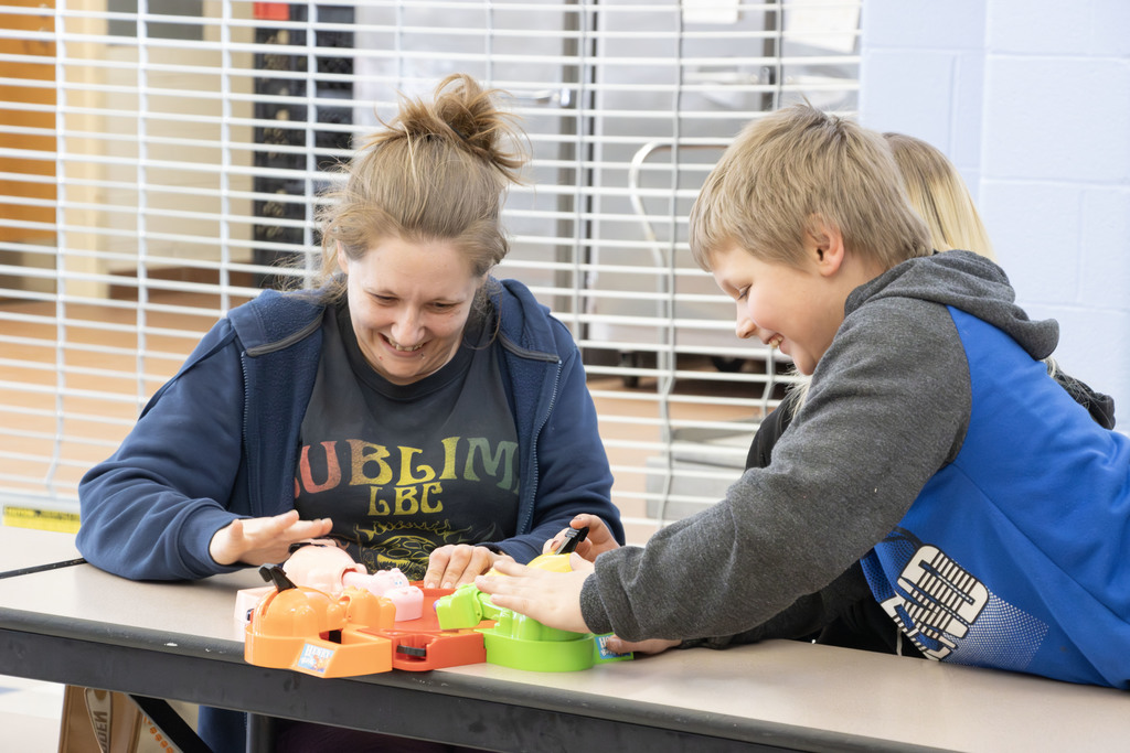 A woman and son play hungry hippos while smiling and laughing