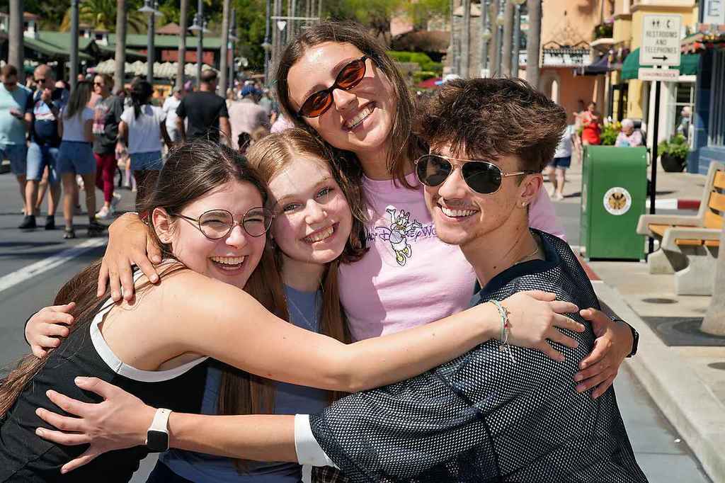 Three current students hugging Jane Cook