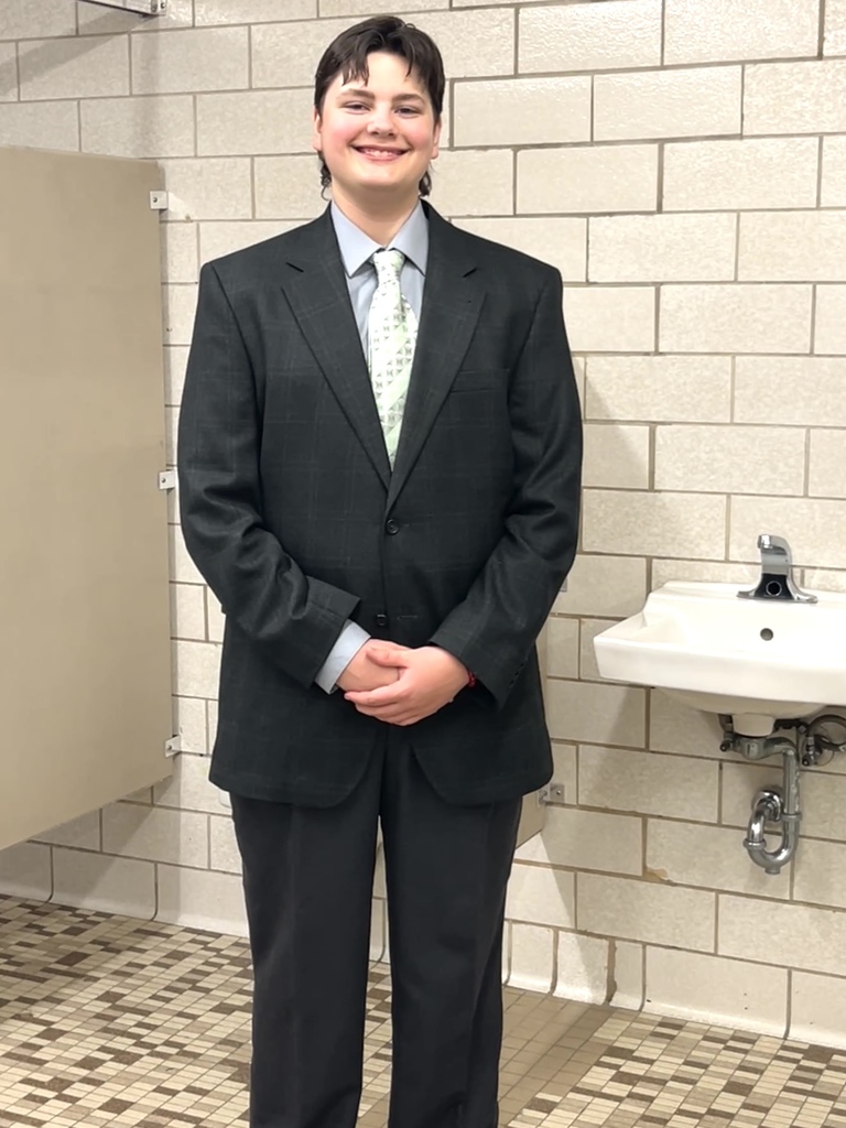 a student smiles while trying on a black tux