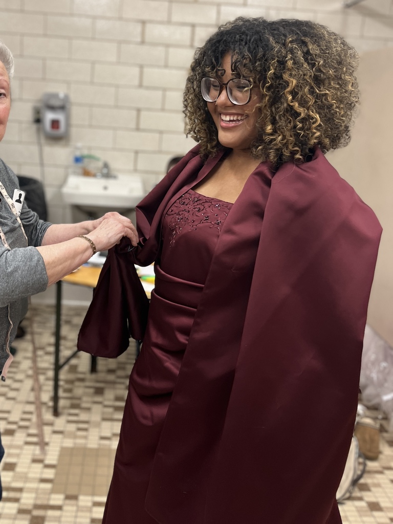 A student smiles while trying on a maroon dress