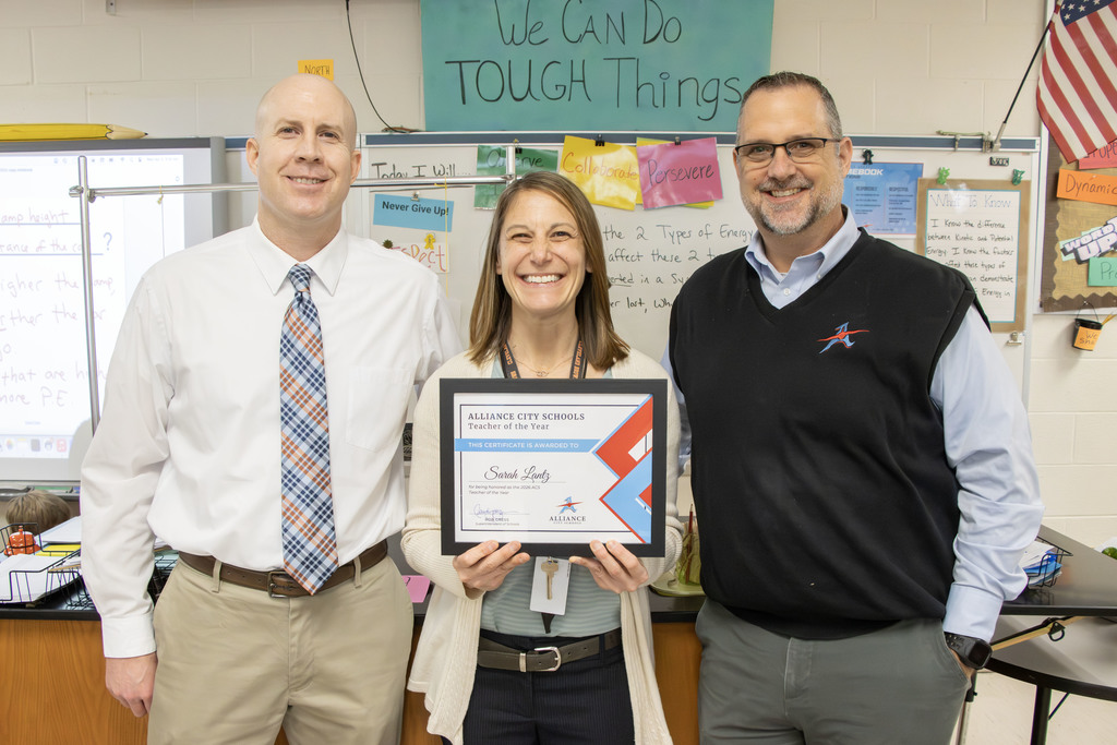 Sarah Lantz smiles while holding her certificate declaring her as the Teacher of the year with Principal Tim Mosher on her left and Superintendent Rob Gress on her right