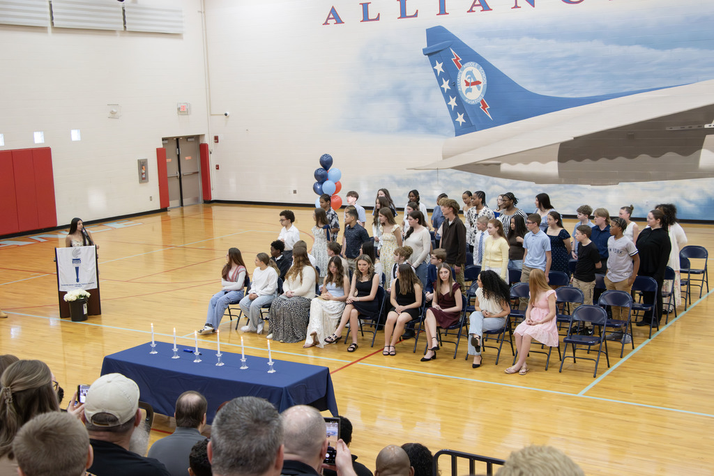 Students sitting in chairs while another student addresses them from the podium