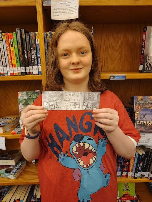 Student holding up the bookmark they designed