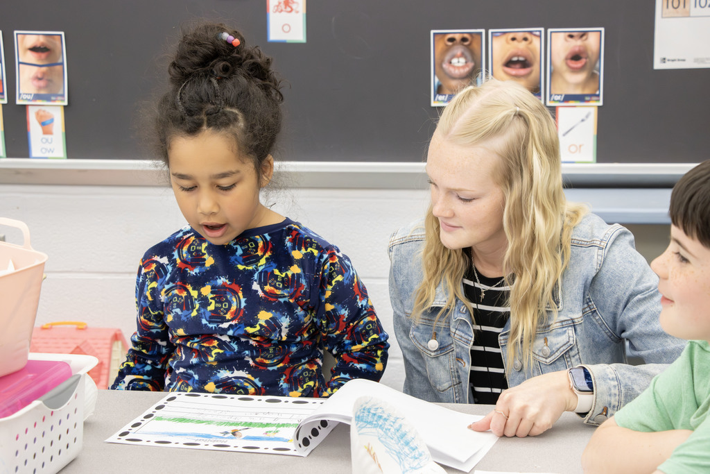 Student reading their book an an adult