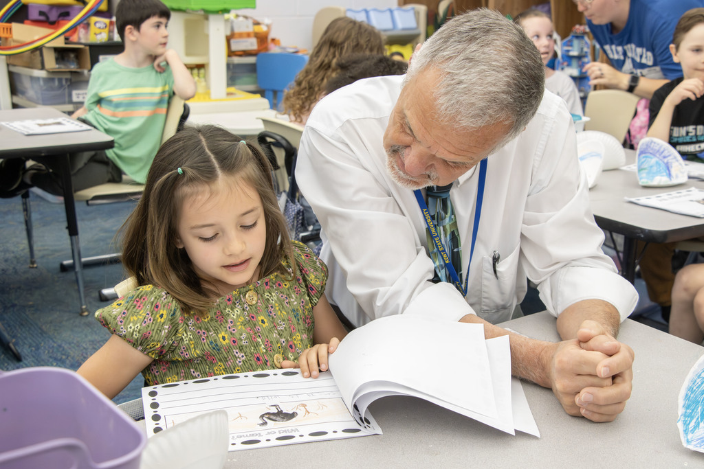 Student reading their book an an adult