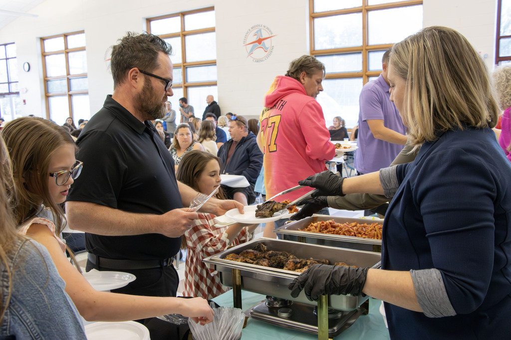 Staff members serving food to students and their parents