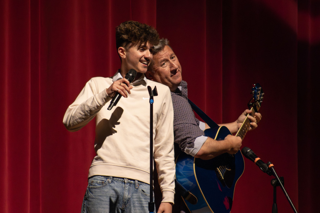 a student singing with his father while the parent plays the guitar