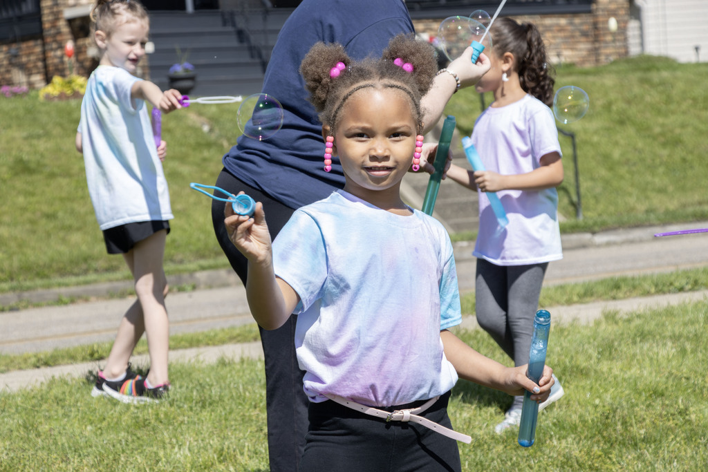 student smiling while making bubbles with a bubble wand