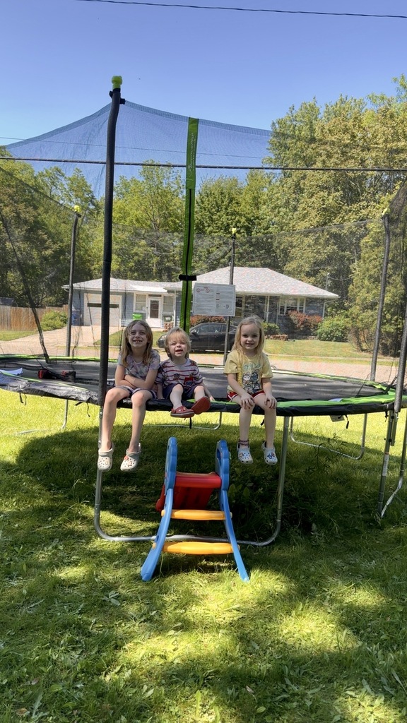 Stella, Piper and Jericho sitting on the trampoline with big smiles on their faces.