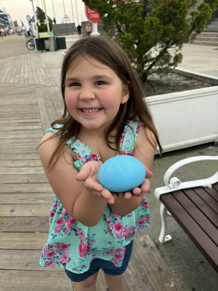 Ellison smiling while holding a dumpling toy on the board walk