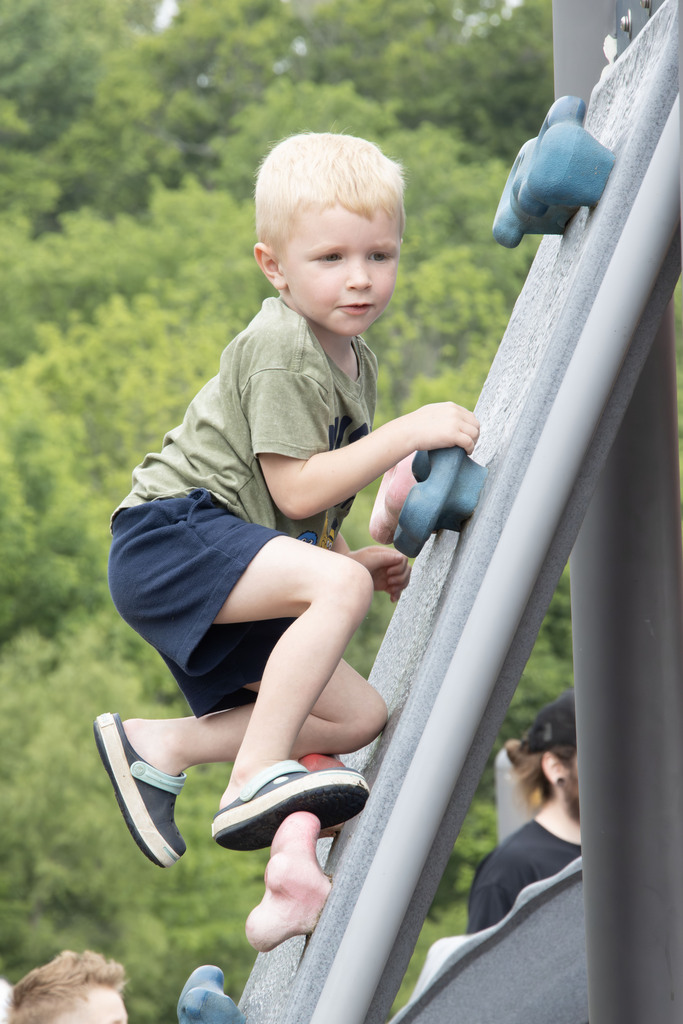 A young child climbs up the rock wall on the playground