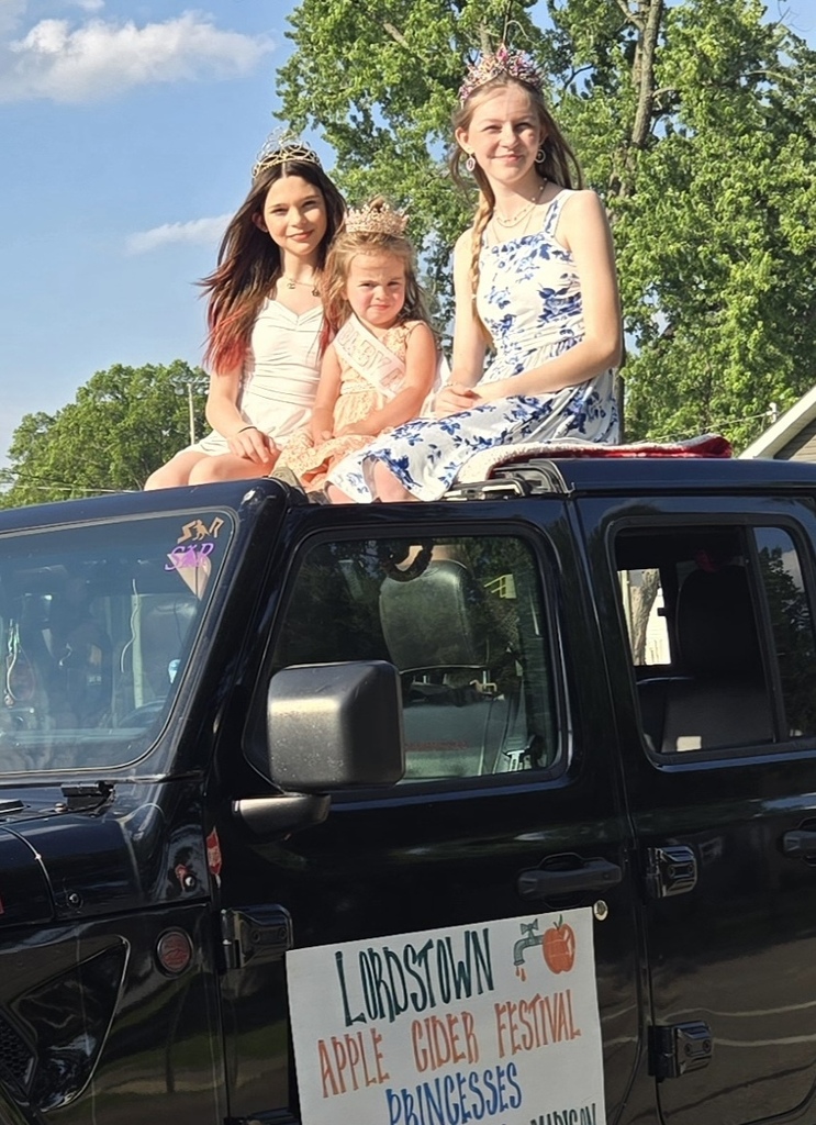 Madison and Brooklyn sitting on a truck wearing their crowns