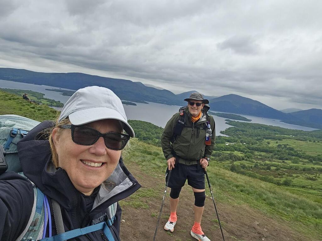 Tracy taking a selfie while her husband stands in the background