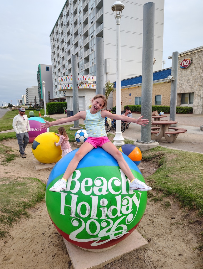 My'Leah siting on a sculpture of a giant beach ball that says "Beach Holiday 2026"