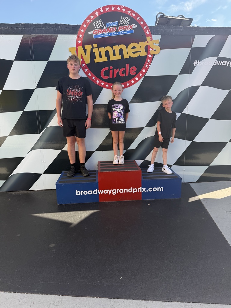 three student standing on the podium after go kart racing
