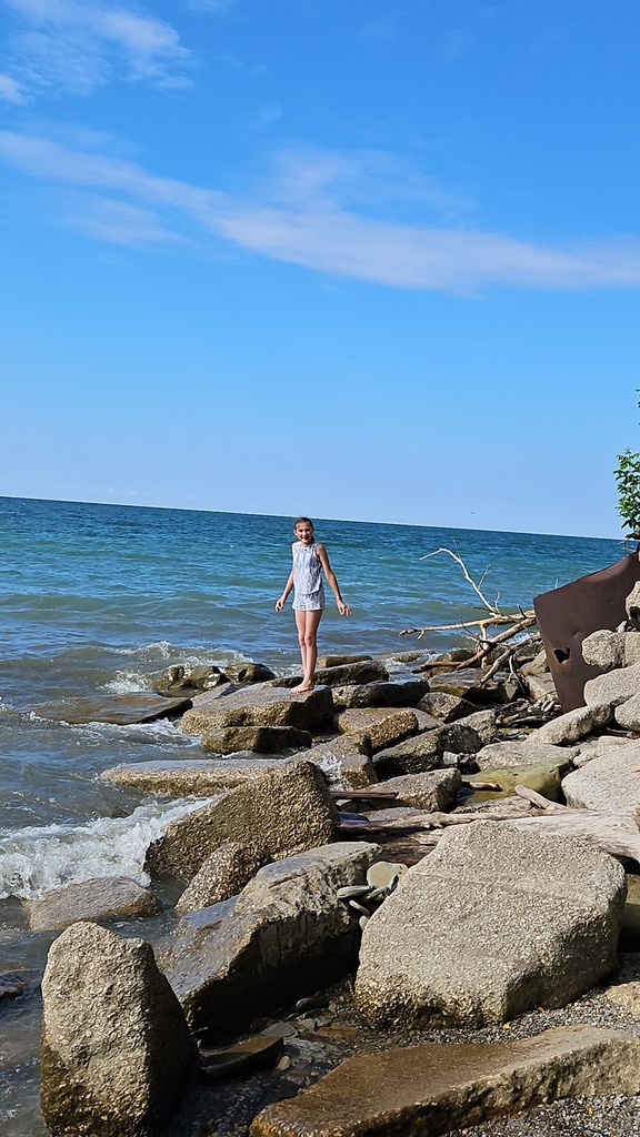 Ava standing on the rocks by lake eriee