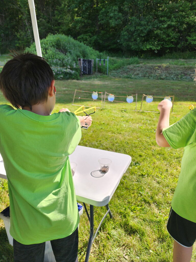 Connor taking aim at a target with a slingshot
