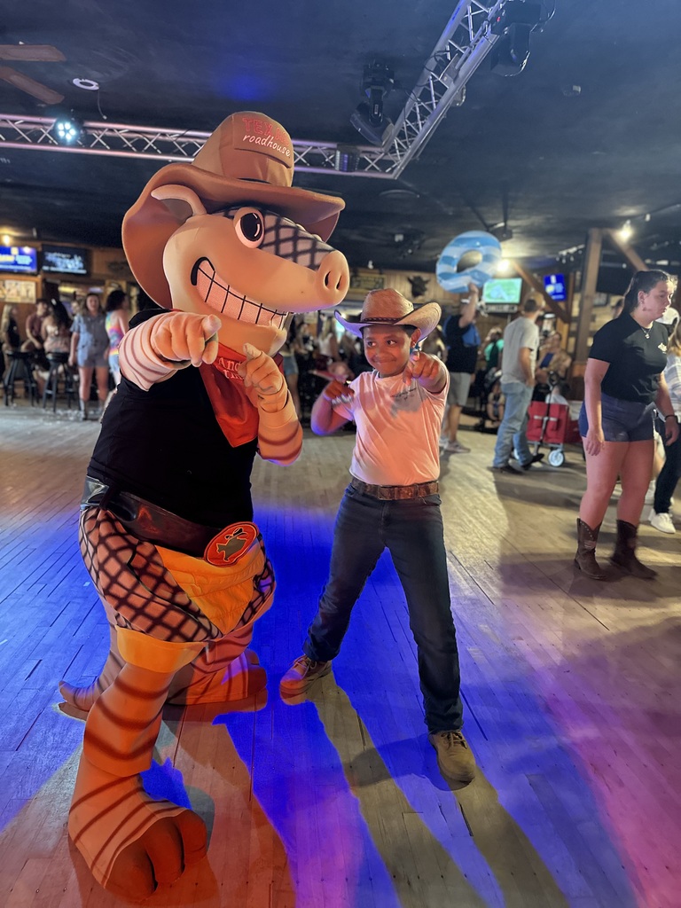 Liam wearing a cowboy hat posting with Andy the Armadillo, the Texas Roadhouse mascot, at the Dusty Armadillo
