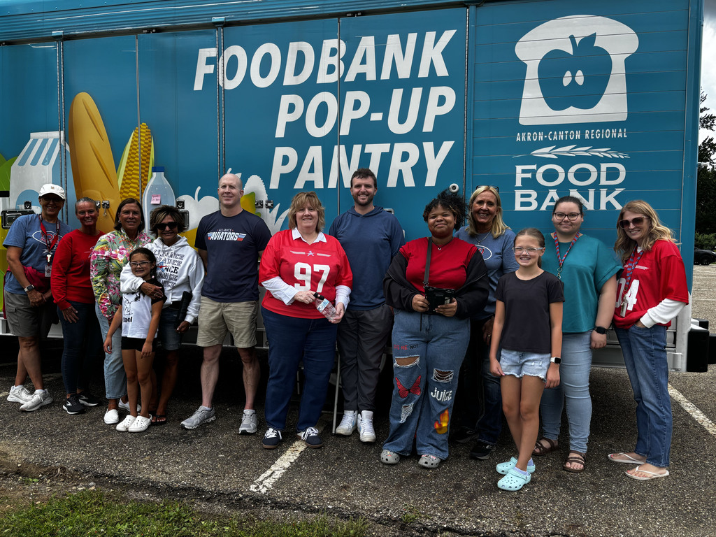 ACS staff members and students post for a picture in front of the food truck that says Foodbank Pop-Up Pantry