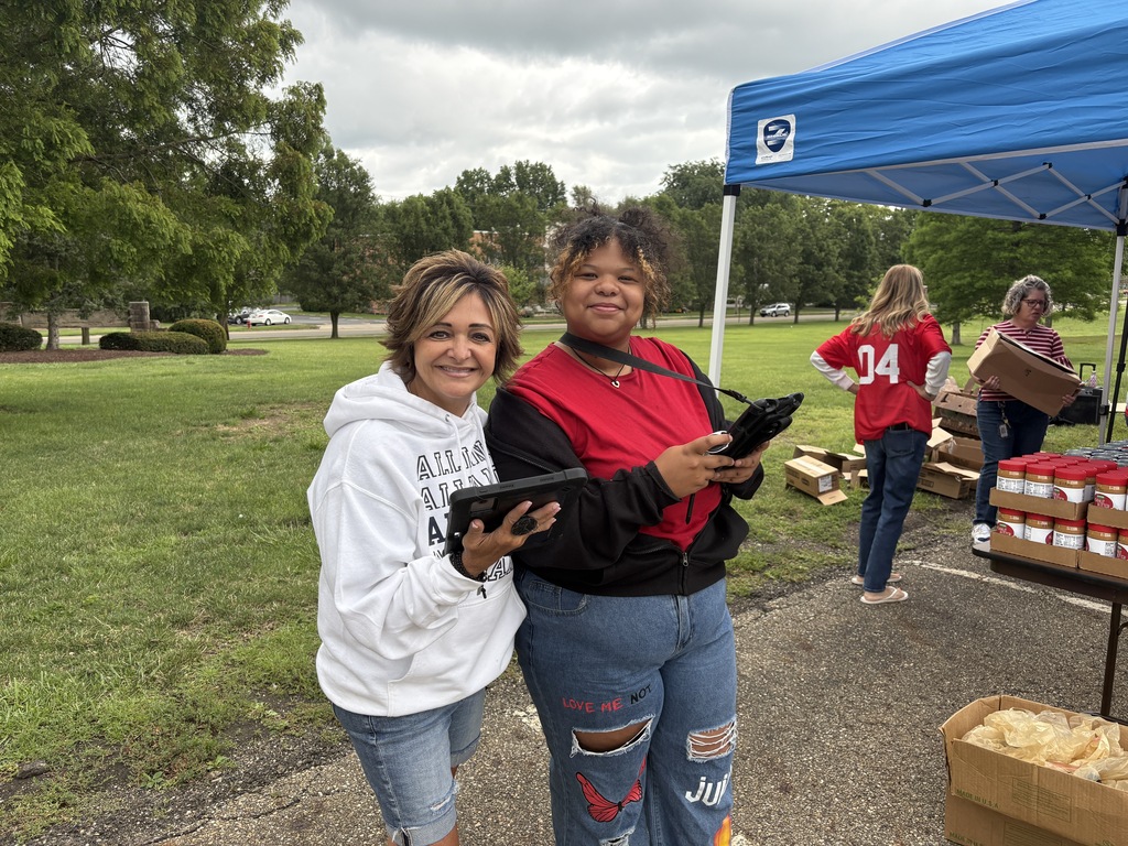 Lori Gasparik and Harmony Thomas hold ipads as they prepare to check community members into the pop-up pantry