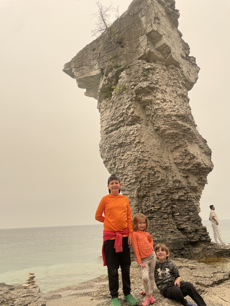 Students standing in front of a rock formation on the beach