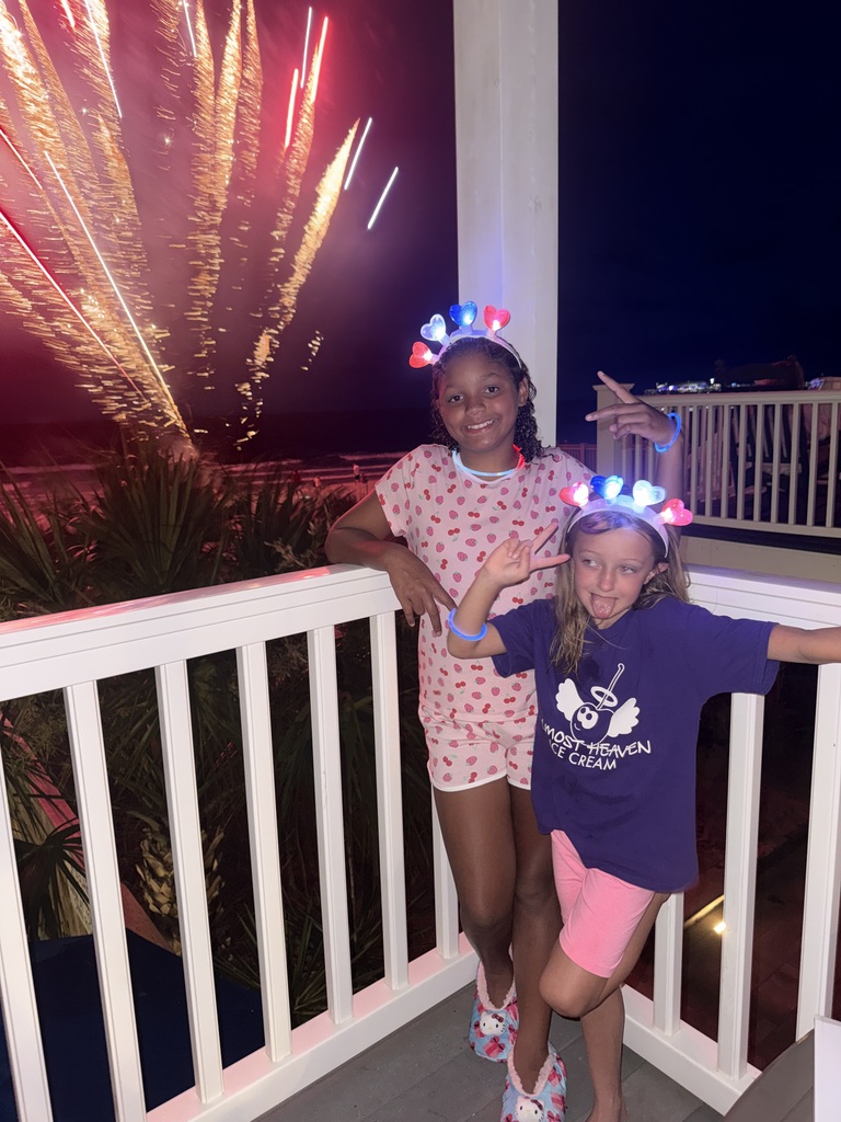 Avi and Margaret standing on a balcony with fireworks in the background