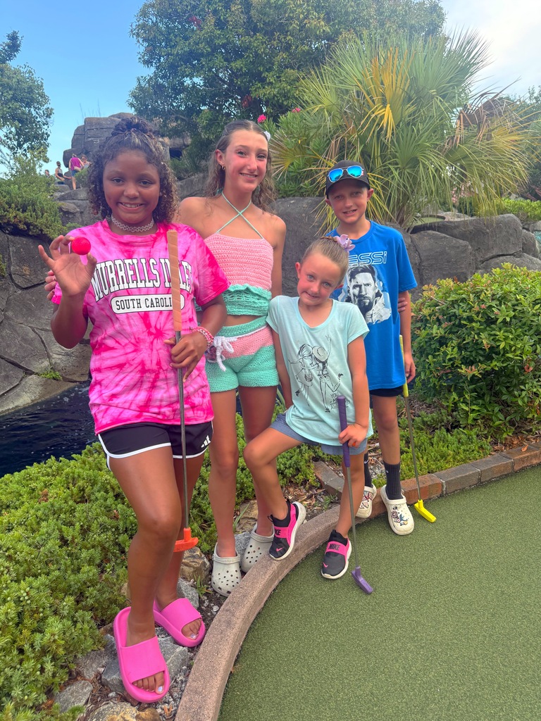 The kids standing together as a putt putt course