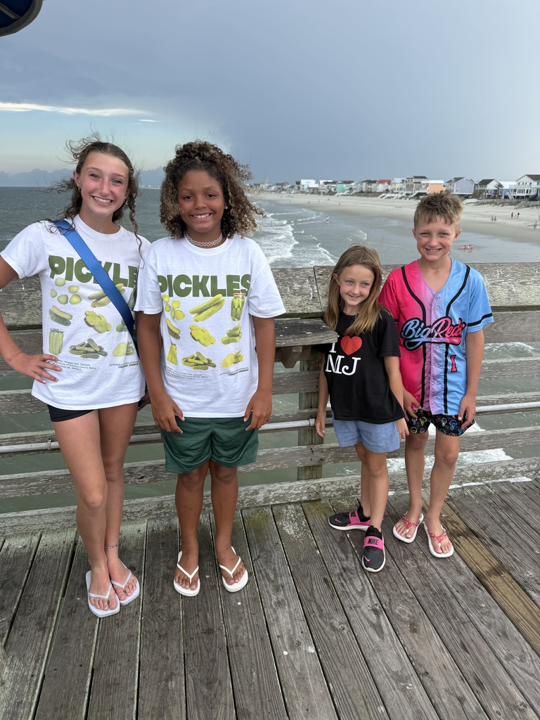 the family standing together on a pier with the beach in the background