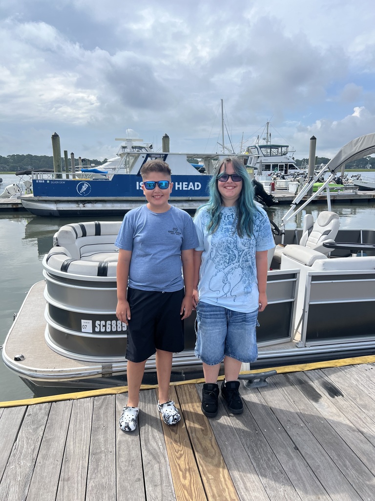 Noah and Lincoln standing on a dock in front of a pontoon boat