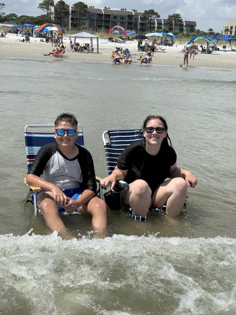 Noah and Lincoln sitting in the ocean on lawn chairs