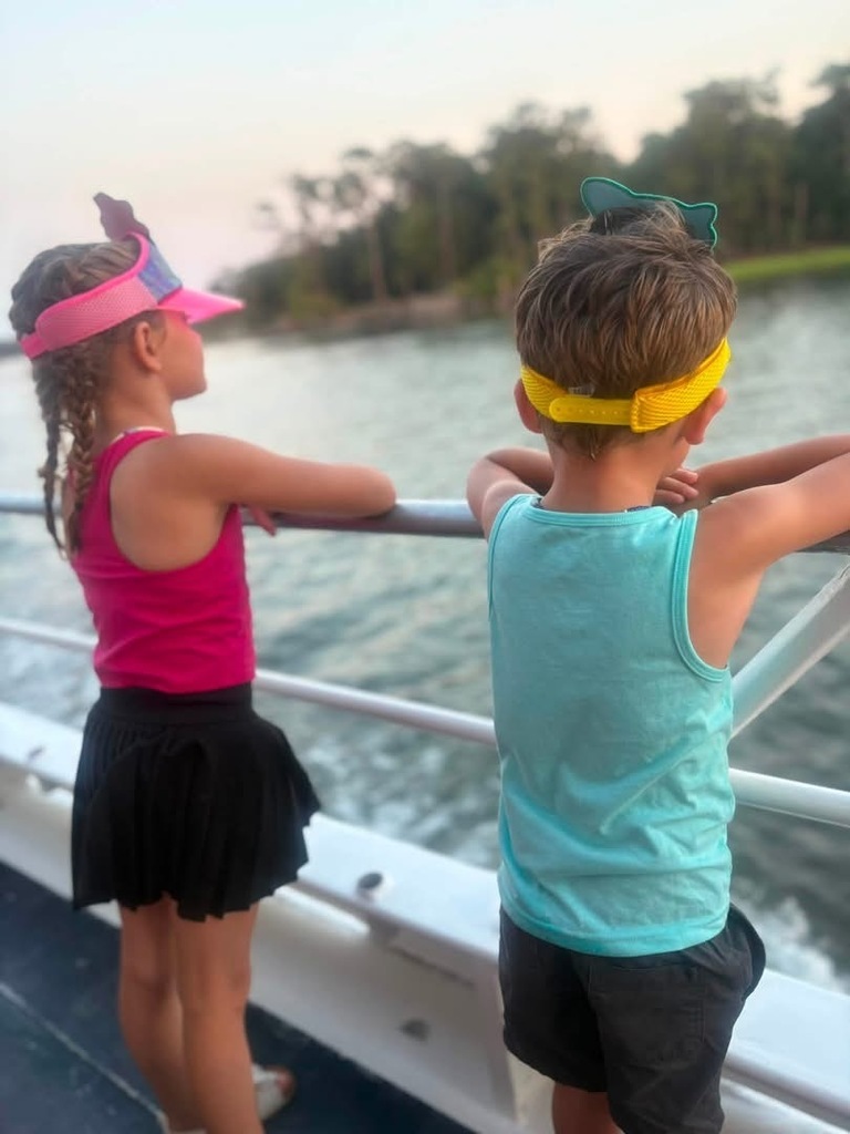 Gracie and another child standing at the railing of a boat looking out at the water