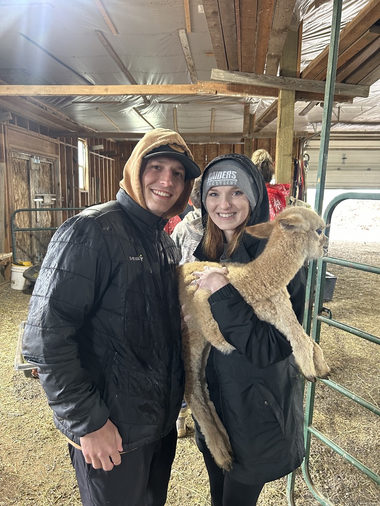 Haley and her husband holding a small farm animal in a barn