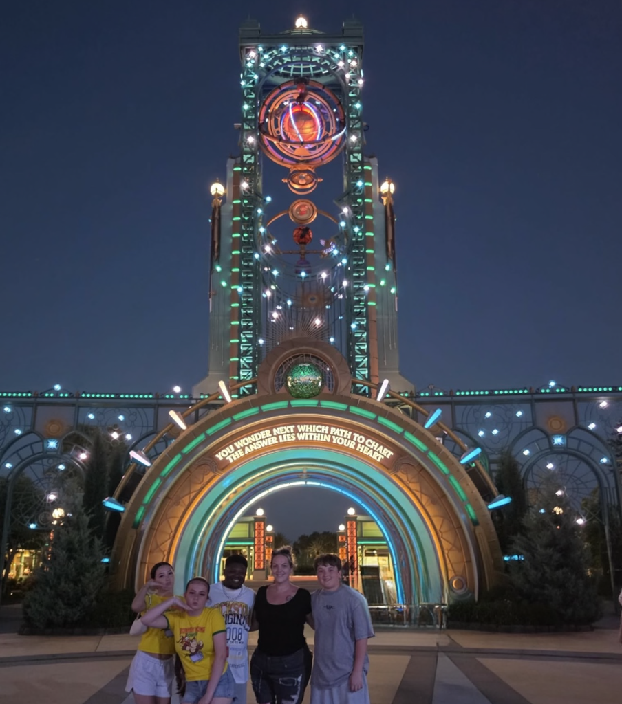 The family standing in the entrance of Epic Universe at night